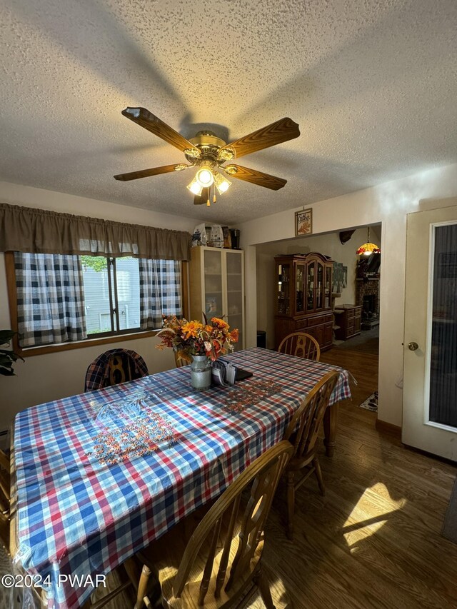 dining room featuring a textured ceiling, ceiling fan, and dark wood-type flooring