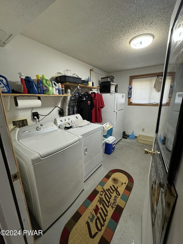 clothes washing area with washer and clothes dryer and a textured ceiling