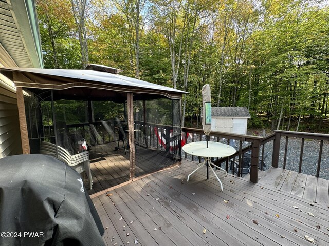 wooden deck featuring a gazebo, a storage unit, and a grill