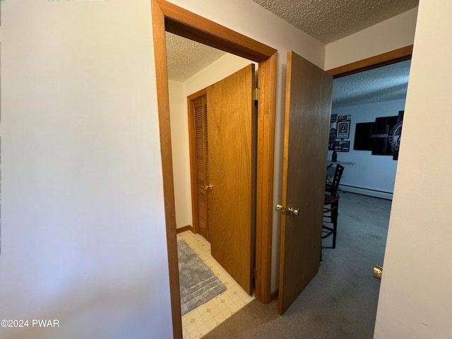 hallway with a textured ceiling and a baseboard heating unit