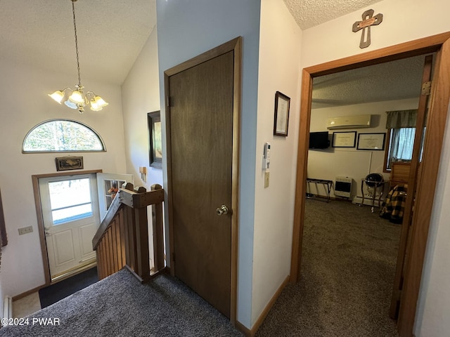 carpeted foyer entrance featuring a notable chandelier, lofted ceiling, a textured ceiling, and a wall unit AC