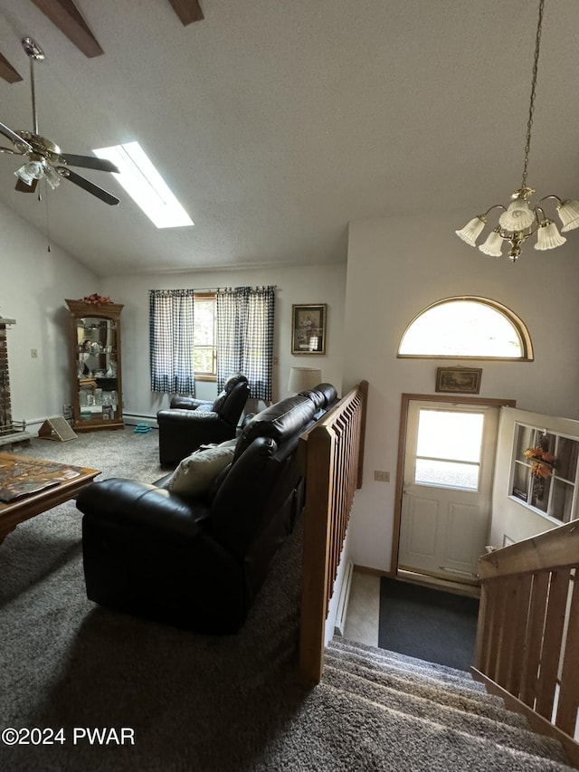 carpeted living room featuring a fireplace, a textured ceiling, ceiling fan with notable chandelier, and lofted ceiling with skylight