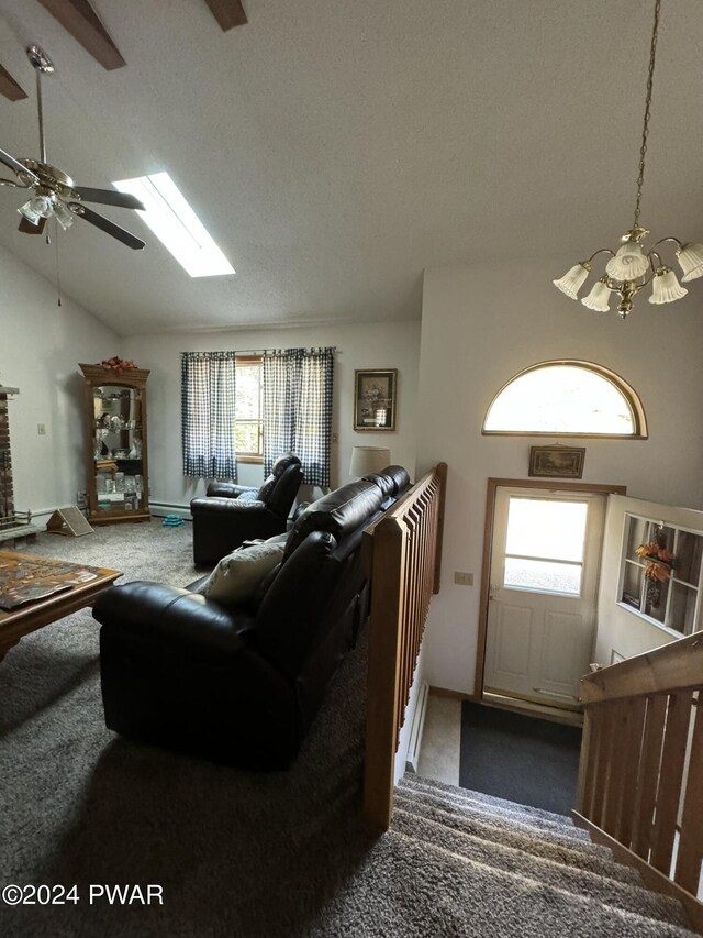 carpeted living room featuring a fireplace, a textured ceiling, ceiling fan with notable chandelier, and lofted ceiling with skylight