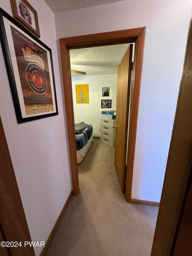 hall featuring light colored carpet and a textured ceiling