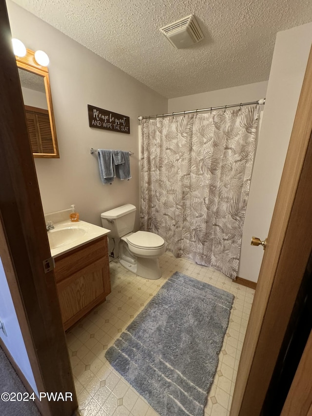 bathroom with vanity, toilet, and a textured ceiling