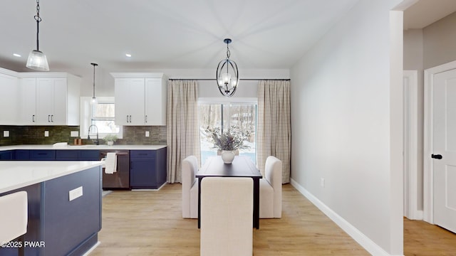 kitchen featuring white cabinetry, stainless steel dishwasher, blue cabinets, and pendant lighting