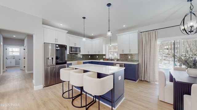 kitchen featuring hanging light fixtures, white cabinetry, appliances with stainless steel finishes, and decorative backsplash