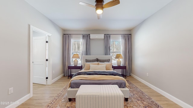 bedroom with a wall mounted air conditioner, ceiling fan, and light hardwood / wood-style floors