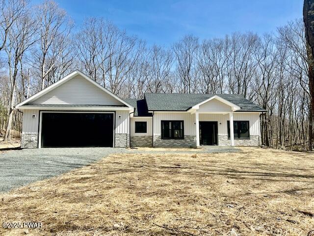 view of front of home with stone siding, a shingled roof, and a garage