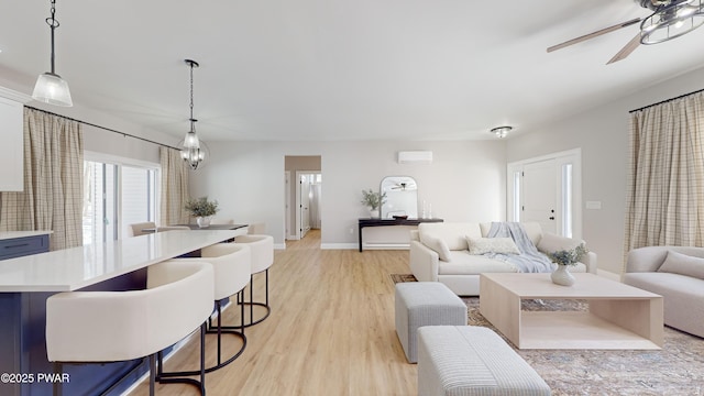 living room with ceiling fan with notable chandelier and light hardwood / wood-style floors