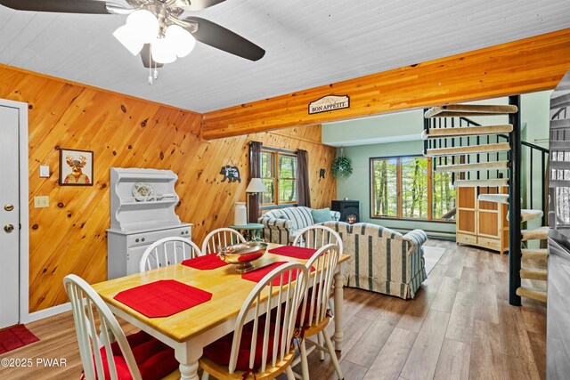191 Water View Dr, Hawley, PA 18428 - dining space with wood walls, stairs, ceiling fan, wood finished floors, and a wood stove