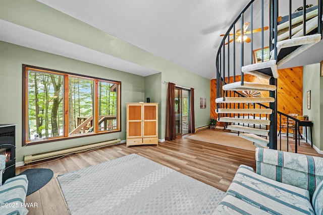 191 Water View Dr, Hawley, PA 18428 - living area featuring a baseboard heating unit, plenty of natural light, stairway, wood finished floors, and lofted ceiling