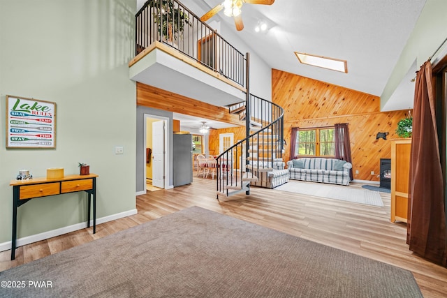 191 Water View Dr, Hawley, PA 18428 - unfurnished living room with ceiling fan, high vaulted ceiling, stairway, wooden walls, and wood finished floors