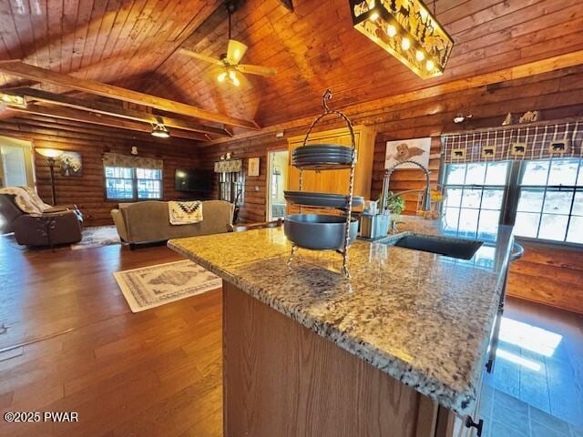 kitchen with wooden ceiling, wood finished floors, a ceiling fan, a sink, and stone counters