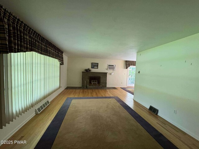 1611 Lake Ariel Hwy, Lake Ariel, PA 18436 - unfurnished living room featuring wood finished floors, a fireplace with flush hearth, baseboards, and a wall mounted AC