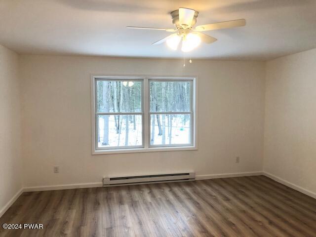 unfurnished room with dark hardwood / wood-style flooring, a baseboard radiator, and ceiling fan