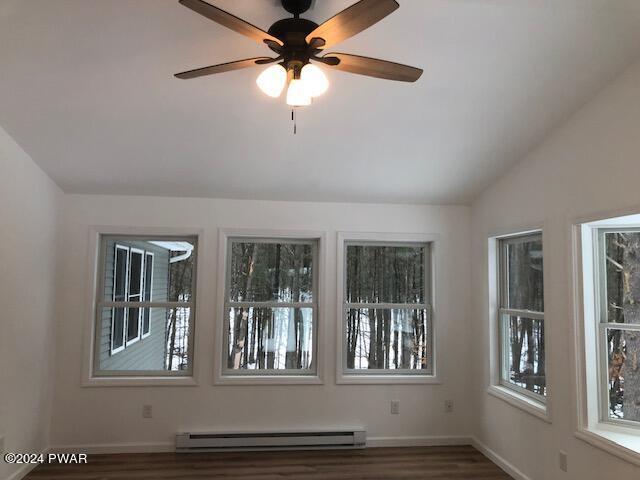 spare room featuring dark hardwood / wood-style flooring, lofted ceiling, ceiling fan, and a baseboard heating unit