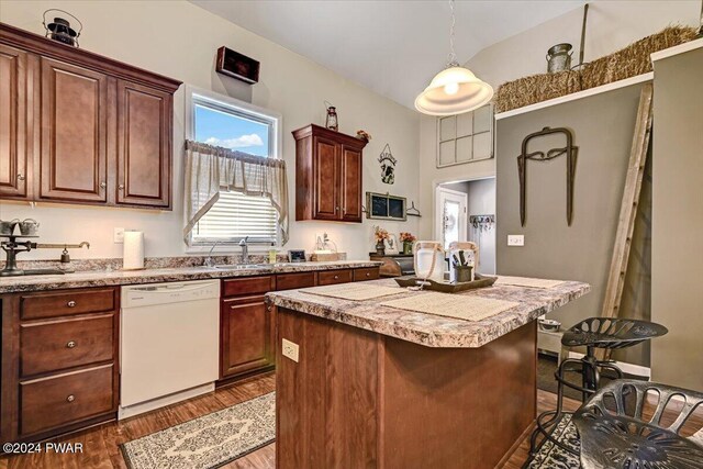 kitchen with dishwasher, sink, hanging light fixtures, a breakfast bar, and a kitchen island