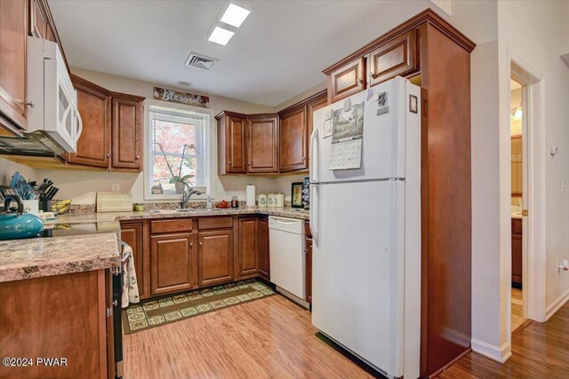 kitchen with light stone countertops, light hardwood / wood-style flooring, white appliances, and sink