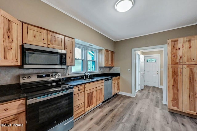 kitchen with decorative backsplash, appliances with stainless steel finishes, light brown cabinetry, sink, and light hardwood / wood-style flooring