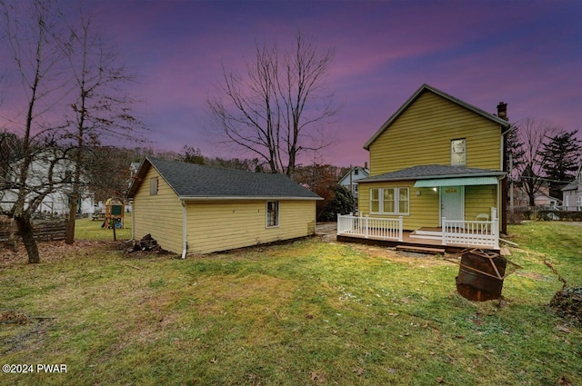 back house at dusk with a deck and a yard