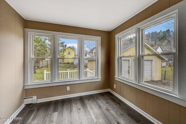 unfurnished sunroom featuring a wealth of natural light and a baseboard heating unit