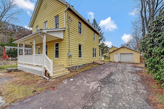 view of side of home with a porch, a garage, and an outdoor structure