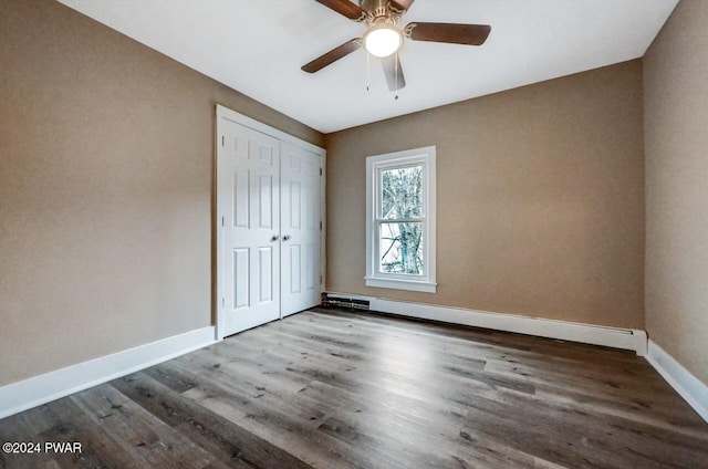 unfurnished bedroom with ceiling fan, a closet, wood-type flooring, and a baseboard radiator