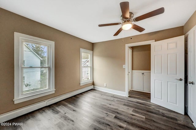 unfurnished bedroom featuring ceiling fan, dark hardwood / wood-style floors, and a baseboard heating unit