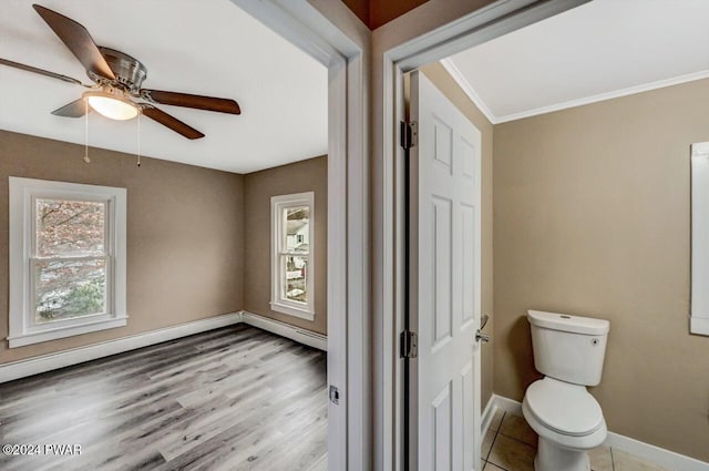 bathroom featuring ceiling fan, hardwood / wood-style flooring, a baseboard heating unit, and toilet