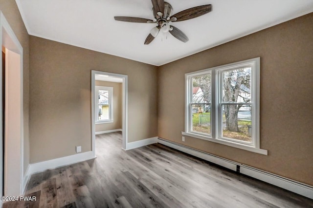 unfurnished room featuring ceiling fan, light hardwood / wood-style flooring, a wealth of natural light, and a baseboard heating unit