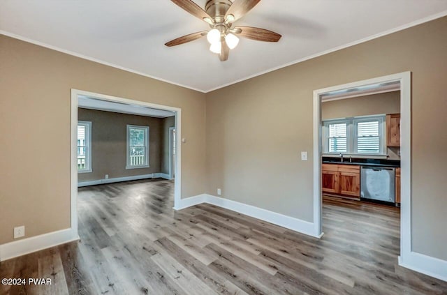 empty room with hardwood / wood-style floors, ceiling fan, crown molding, and sink