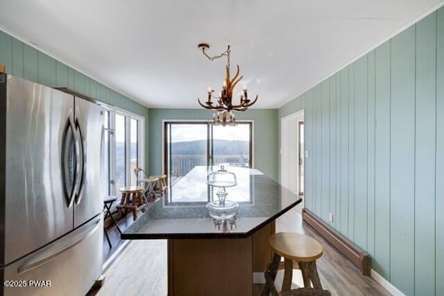 kitchen featuring a center island, wood walls, an inviting chandelier, light hardwood / wood-style flooring, and stainless steel refrigerator