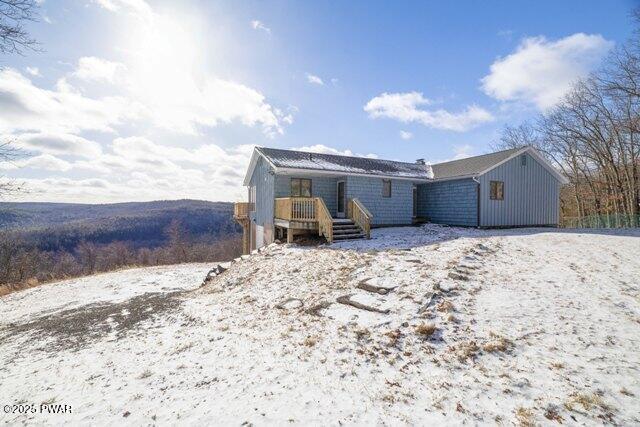 snow covered house featuring a deck