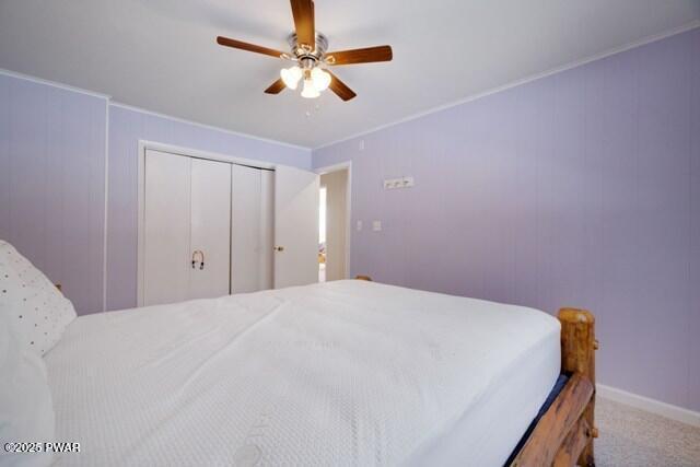 carpeted bedroom with ceiling fan and a closet