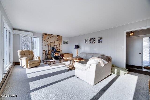 carpeted living room with baseboard heating, a wood stove, and a healthy amount of sunlight