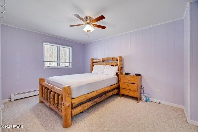 carpeted bedroom featuring ceiling fan, crown molding, and a baseboard heating unit