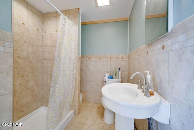 bathroom featuring tile patterned flooring, tile walls, curtained shower, and sink