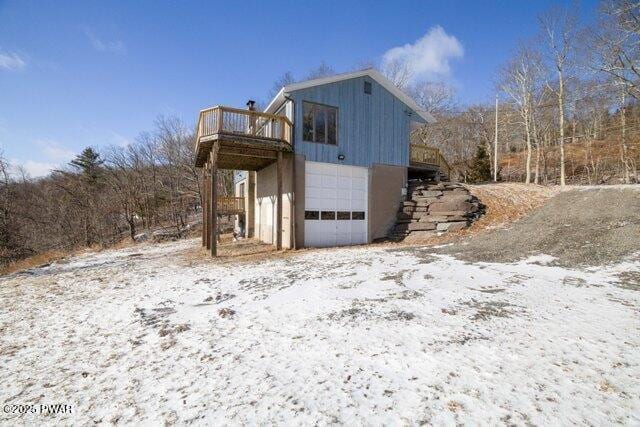 view of snow covered exterior with a garage and a deck