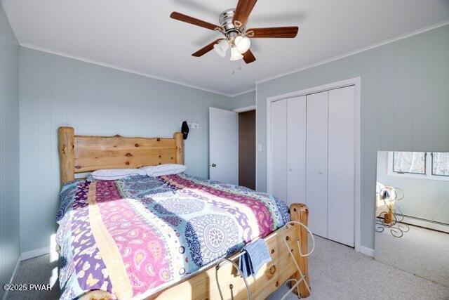 carpeted bedroom featuring ceiling fan, a closet, and ornamental molding