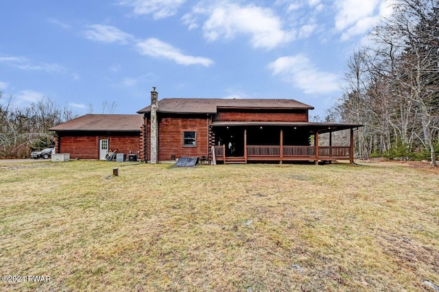 rear view of property with a wooden deck and a lawn