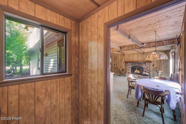 77 Brookfield Rd, Lake Ariel, PA 18436 - carpeted dining space featuring wooden walls, a brick fireplace, and a wooden ceiling with exposed beams