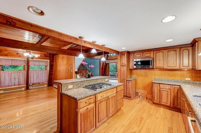 kitchen with pendant lighting, light hardwood / wood-style floors, stainless steel appliances, and wooden walls