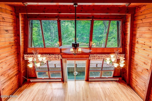 unfurnished sunroom with a baseboard radiator, an inviting chandelier, and a wealth of natural light