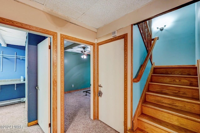 stairway featuring carpet flooring, ceiling fan, and a baseboard heating unit