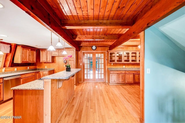 kitchen with french doors, a center island, hanging light fixtures, stainless steel dishwasher, and wooden walls