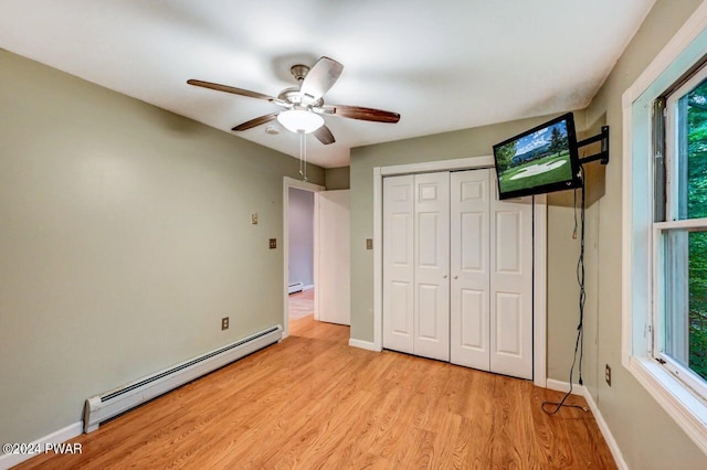 unfurnished bedroom featuring ceiling fan, a closet, light hardwood / wood-style floors, and a baseboard heating unit