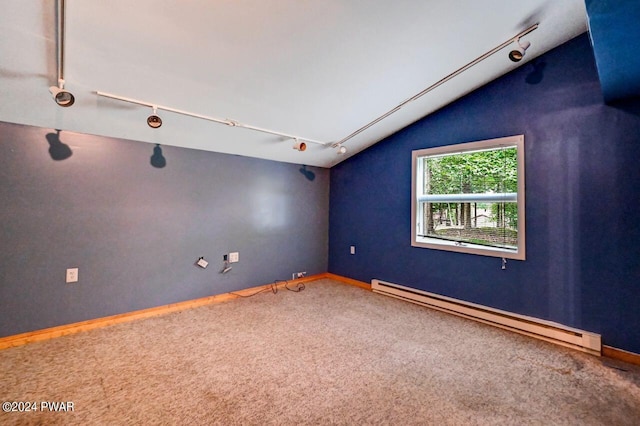 empty room featuring carpet floors, rail lighting, vaulted ceiling, and a baseboard heating unit