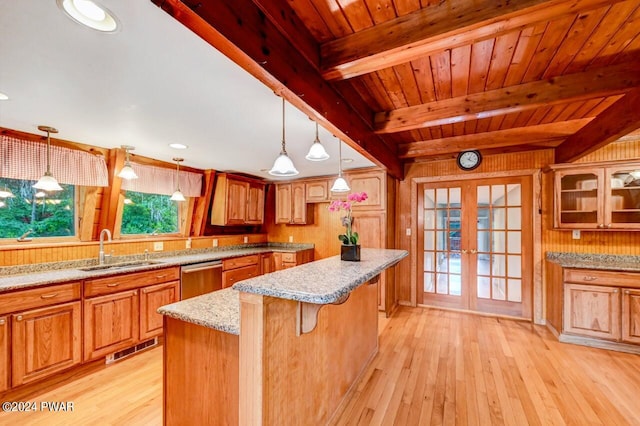 kitchen with wood walls, french doors, sink, beamed ceiling, and a kitchen island