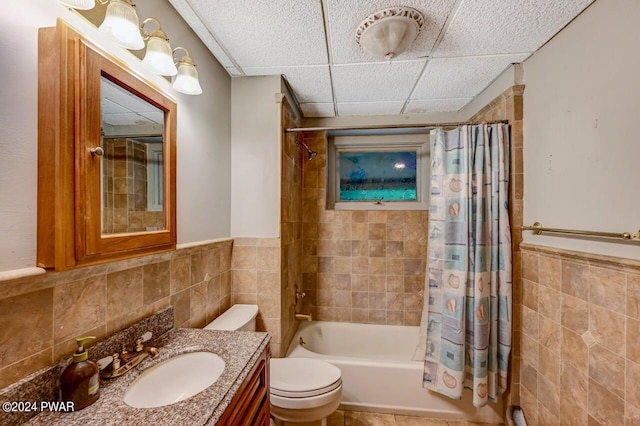 full bathroom featuring shower / tub combo, a paneled ceiling, vanity, tile walls, and toilet